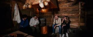 Vier mensen luisteren met koptelefoontjes in sfeervolle ruimte