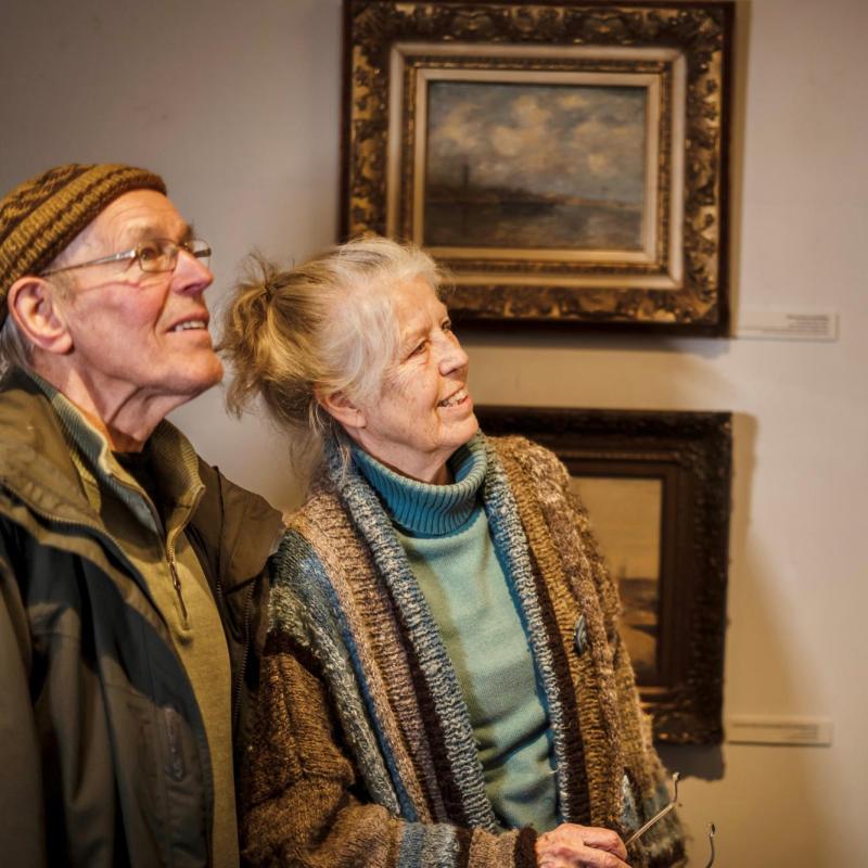 man en vrouw bekijken schilderij in museum