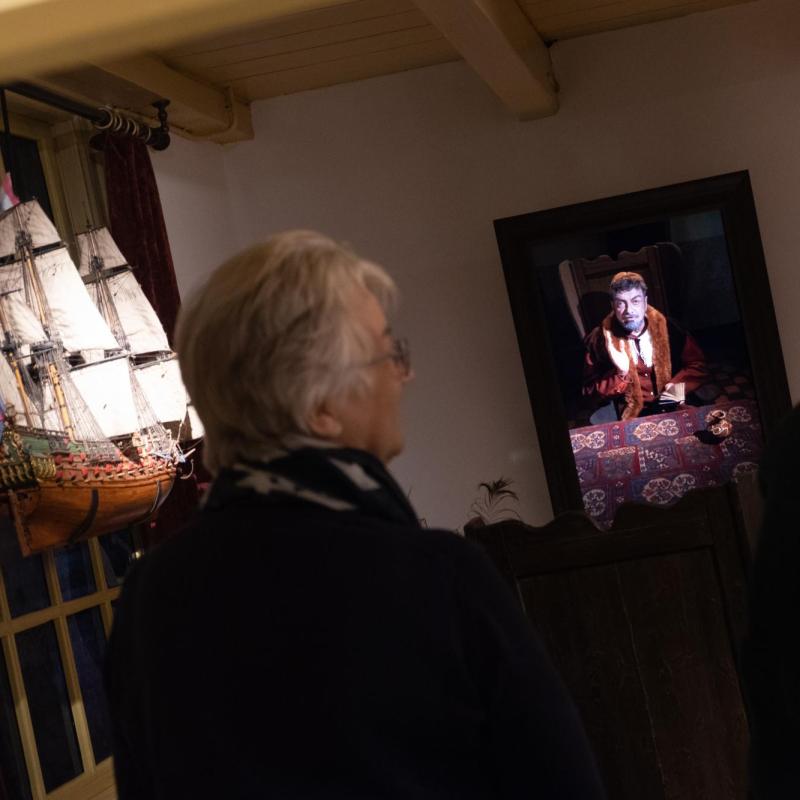 bejaarde vrouw kijkt in tentoonstellingsruimte naar scherm